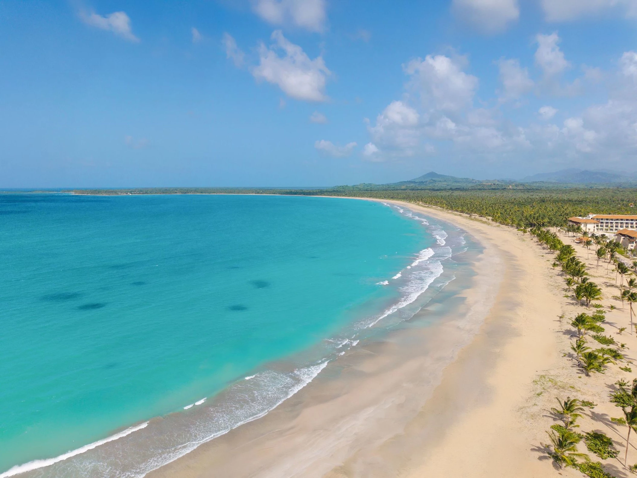 An aerial view of the long, pristine sandy beach and turquoise water at Dreams Playa Esmeralda resort.