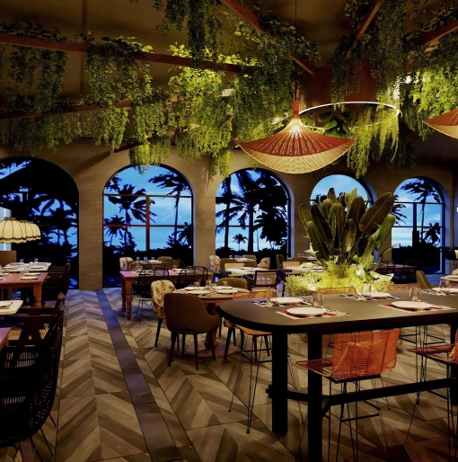 The interior of the Tierra restaurant, decorated with hanging plants, arched windows, and wicker lamps.