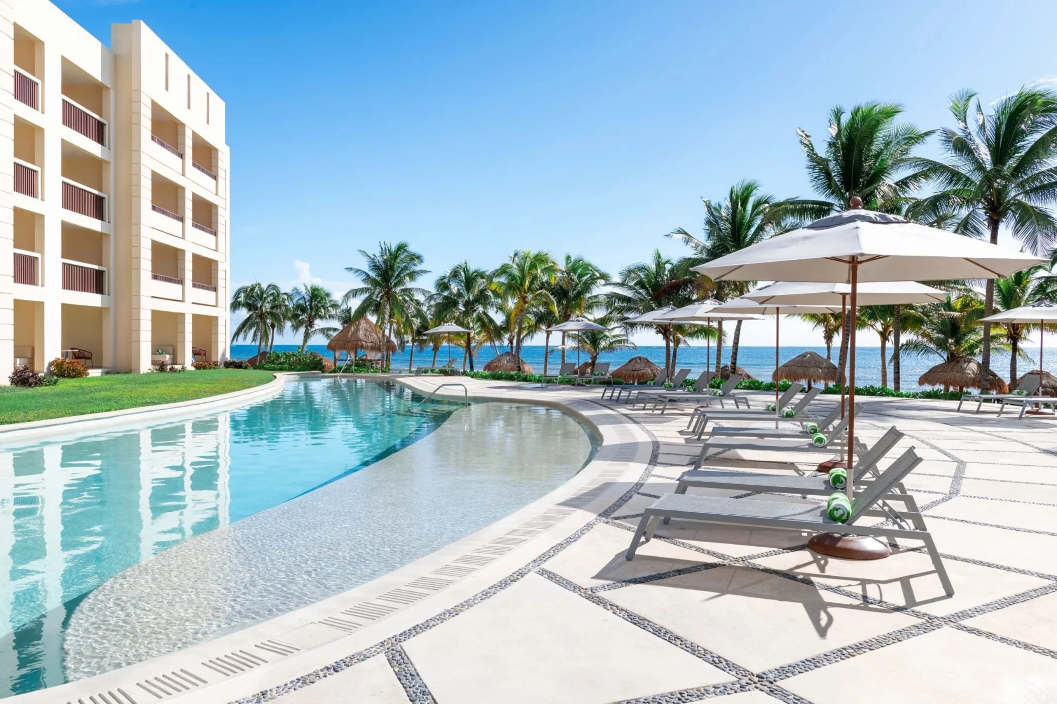 pool and poolside loungers and resort building at Dreams Puerto Morelos Resort & Spa