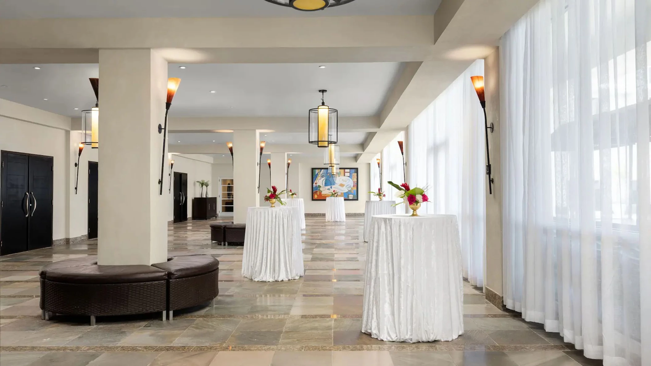 A cocktail set-up in the spacious ballroom foyer of Dreams Rose Hall, with white-draped tables and lighting.