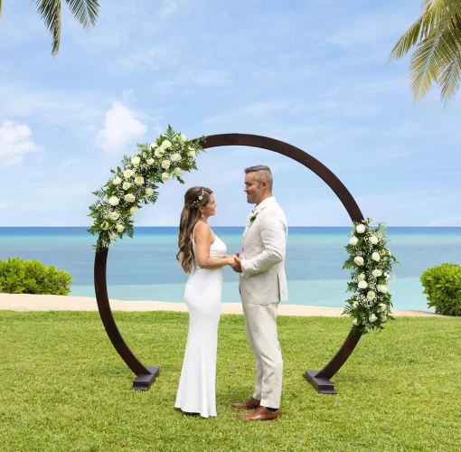 A bride and groom standing at the resort's West Lawn wedding venue with the ocean in the background.
