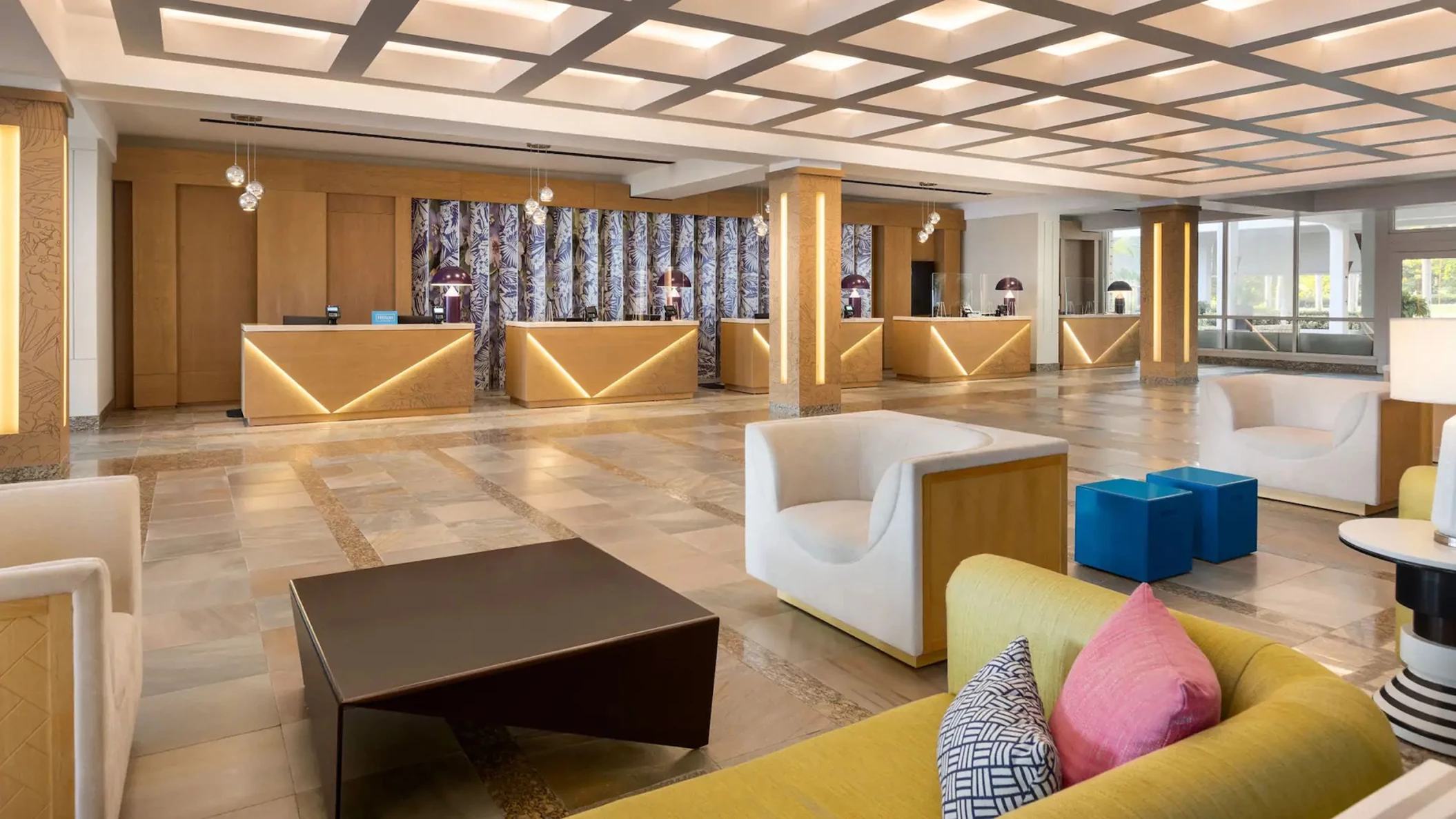 The elegant and modern entrance lobby of Dreams Rose Hall Resort & Spa with stylish furniture and reception desks.