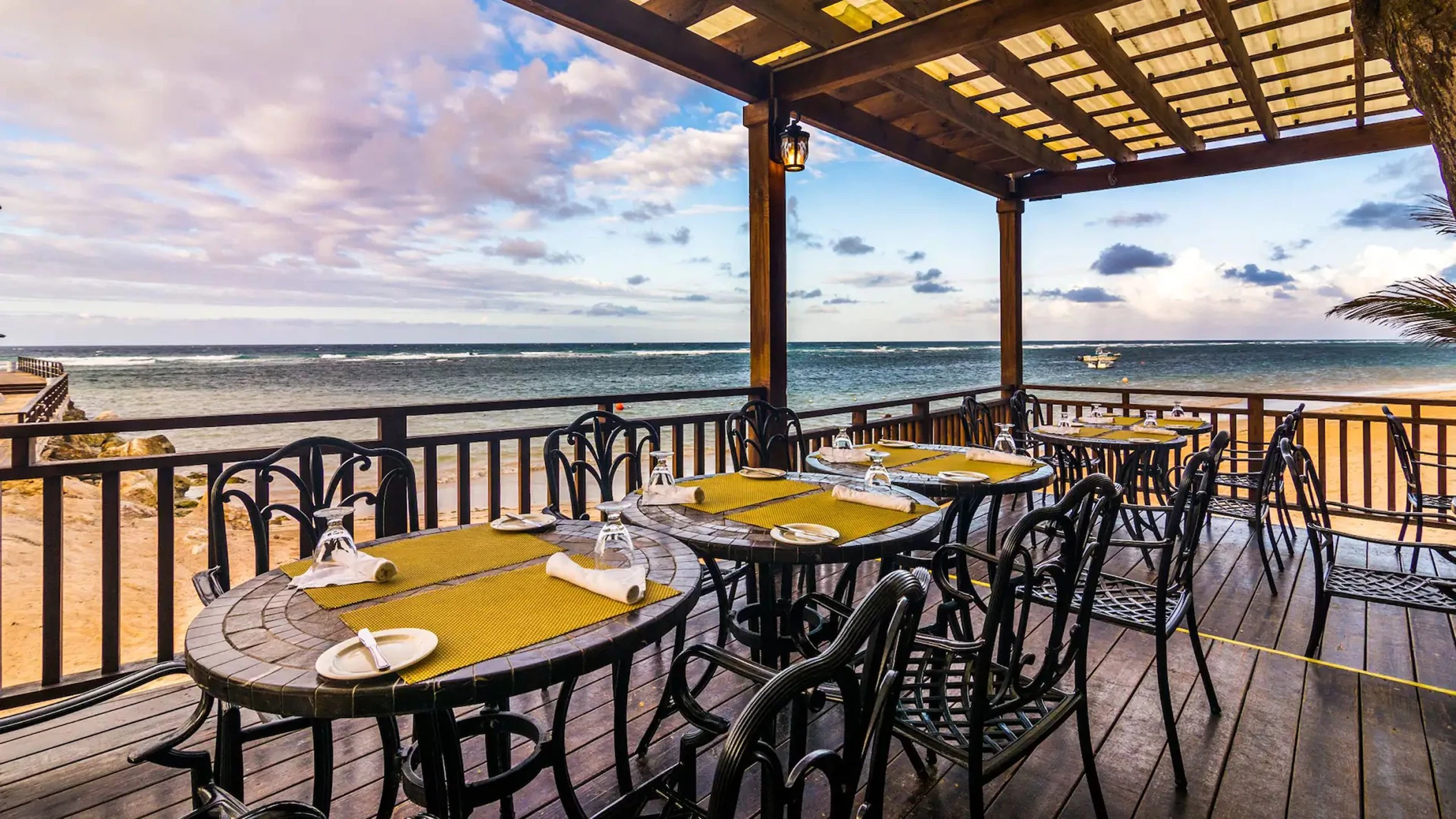 The Moonstone Di Mare restaurant's outdoor deck with dining tables, chairs, and a breathtaking ocean view.
