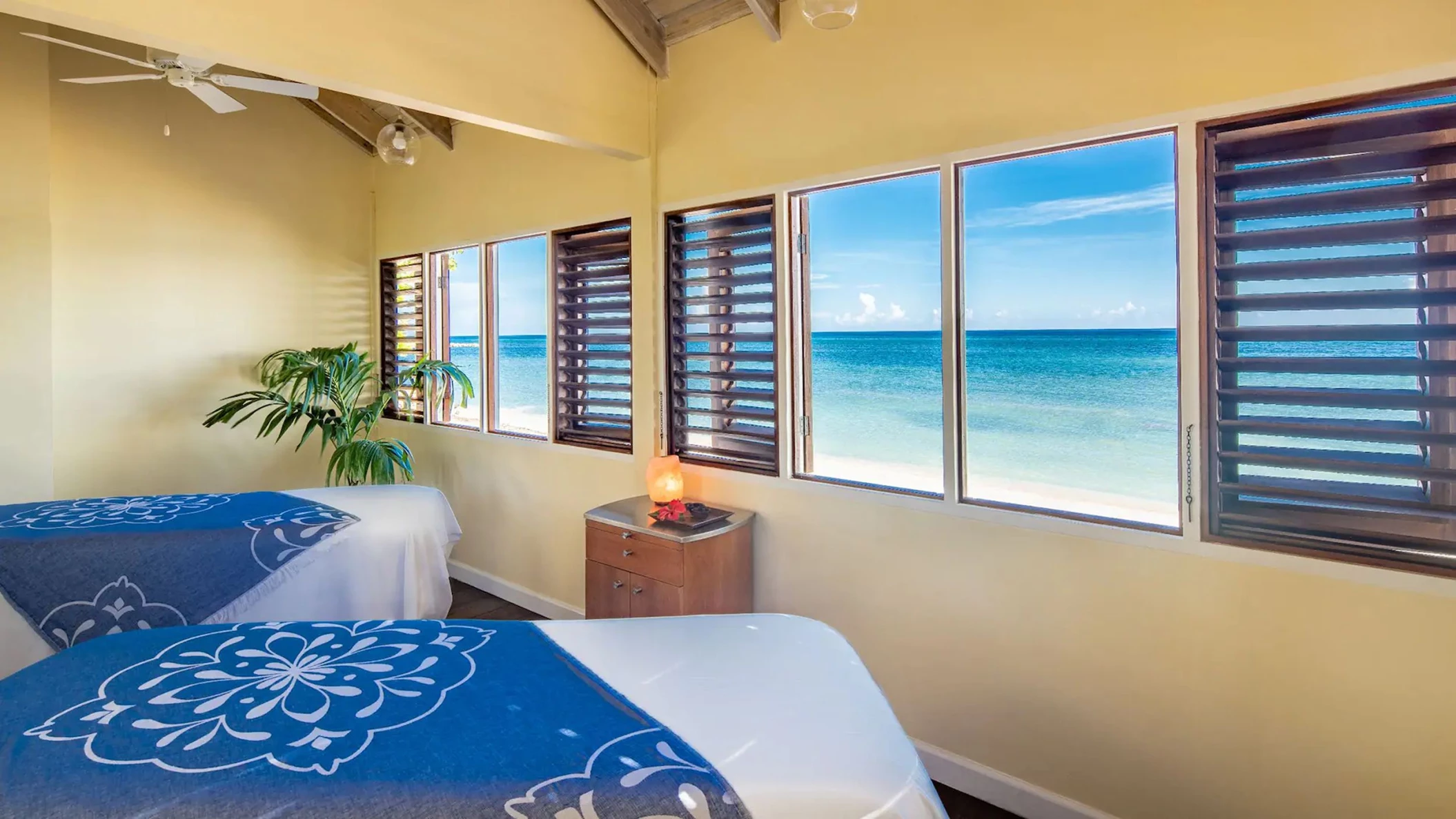 The tranquil interior of the Spa by the Sea, with two massage tables and large windows facing the ocean.