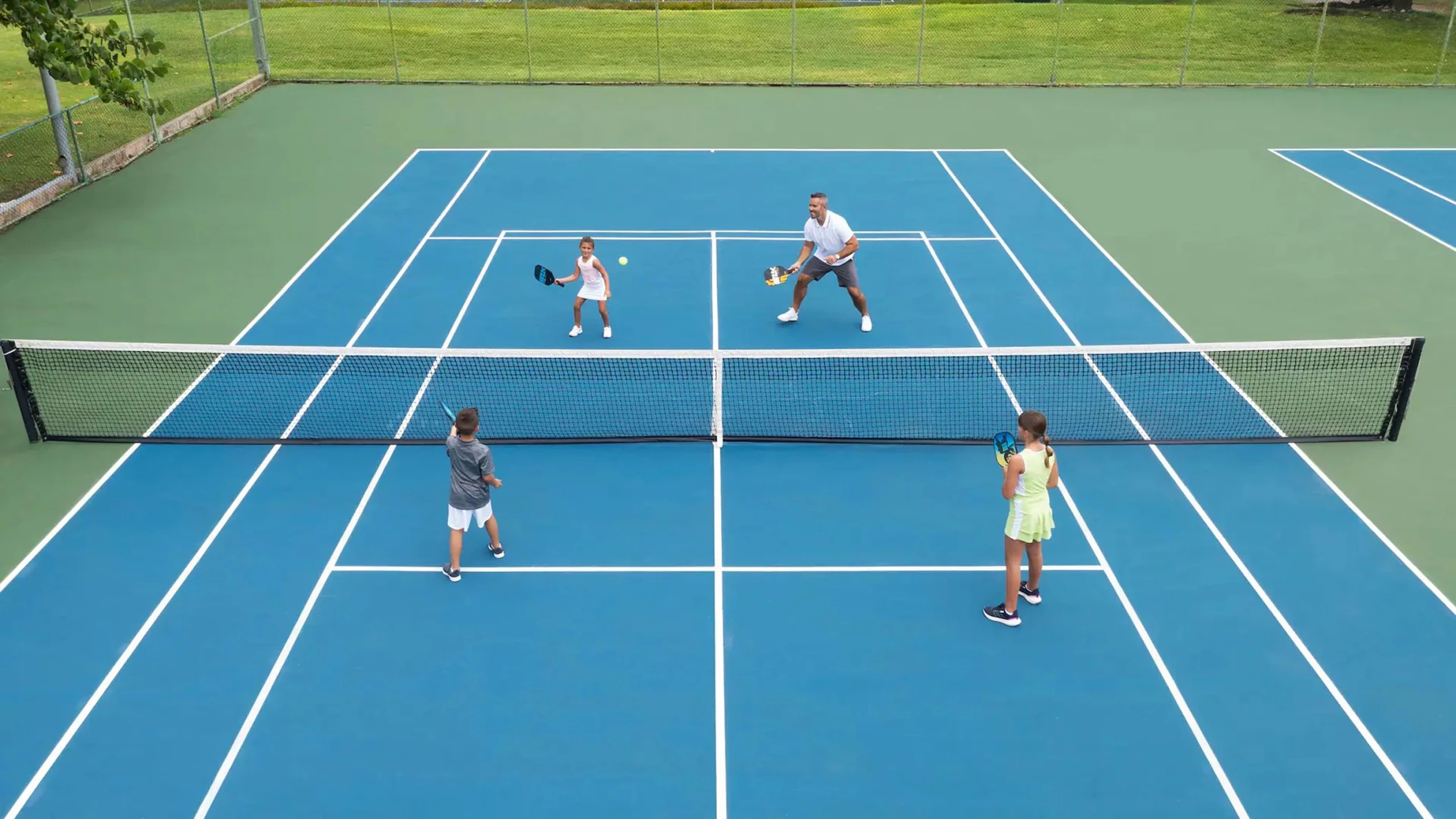 A family playing a game of tennis on one of the resort's well-maintained blue and green tennis courts.