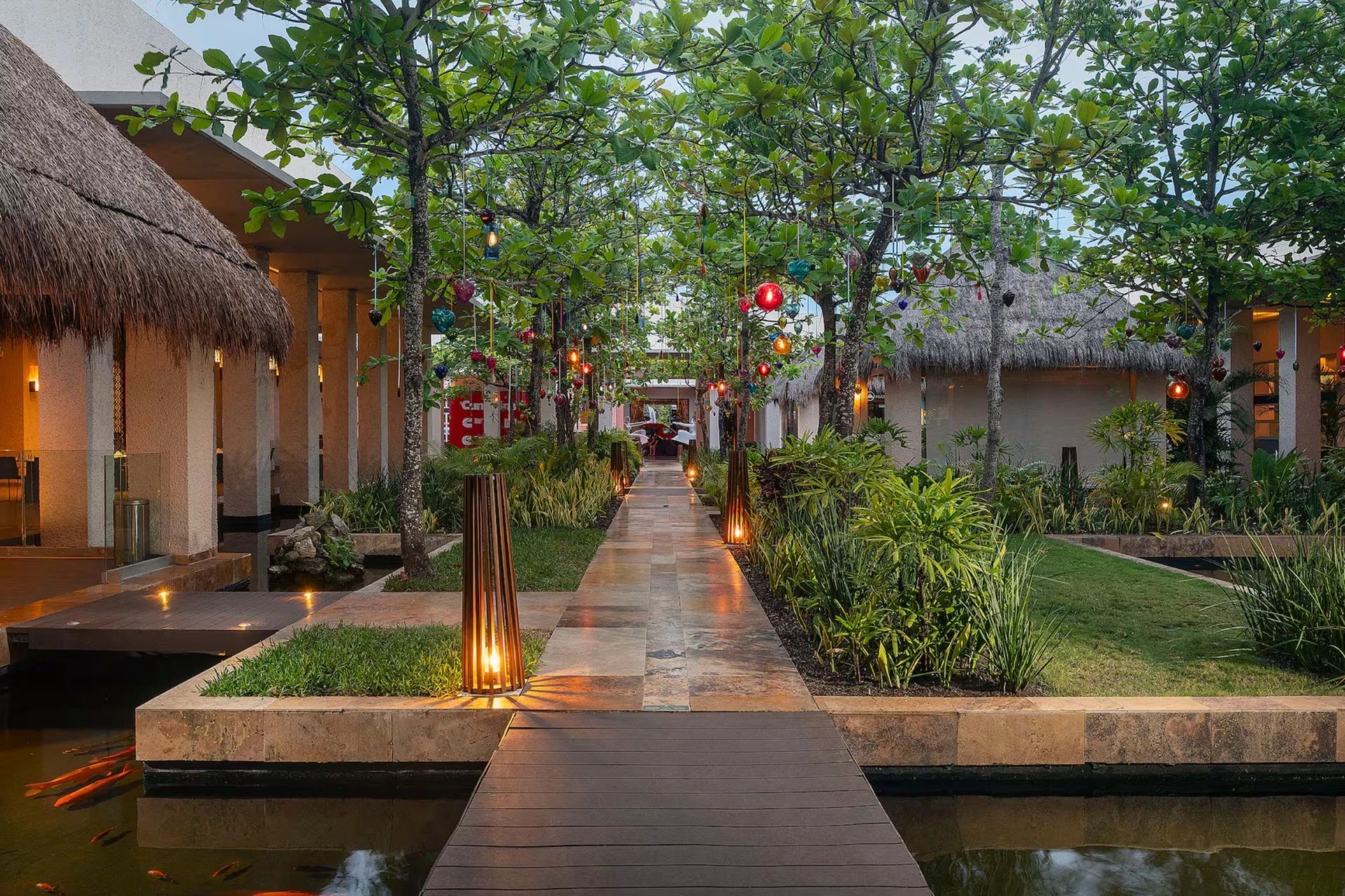pathway lit by lanterns surrouded by lush greenery and resort buildings at Paradisus Playa Del Carmen