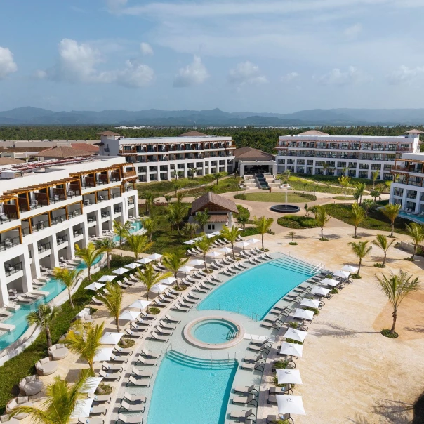 An aerial view of the Secrets Playa Esmeralda resort with a large pool, lounge chairs, and buildings.