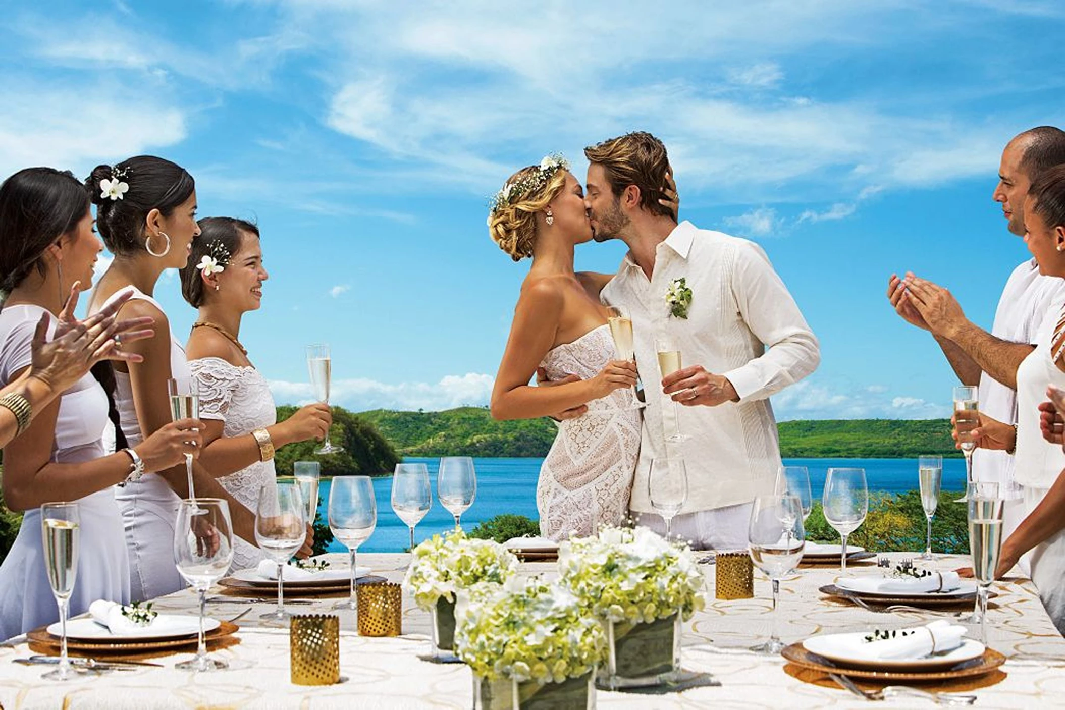 A newly married couple and their guests celebrating with champagne, overlooking a beautiful ocean view.
