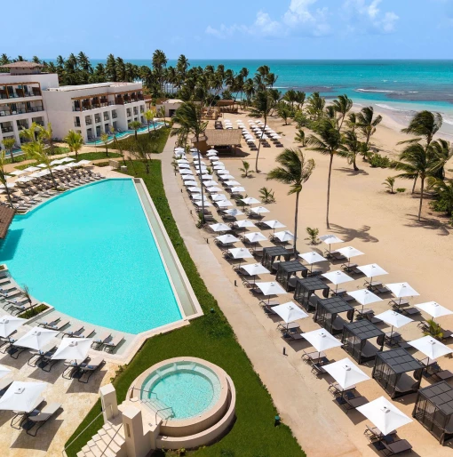 A large, multi-level swimming pool area with a hot tub and many lounge chairs for guests to relax.