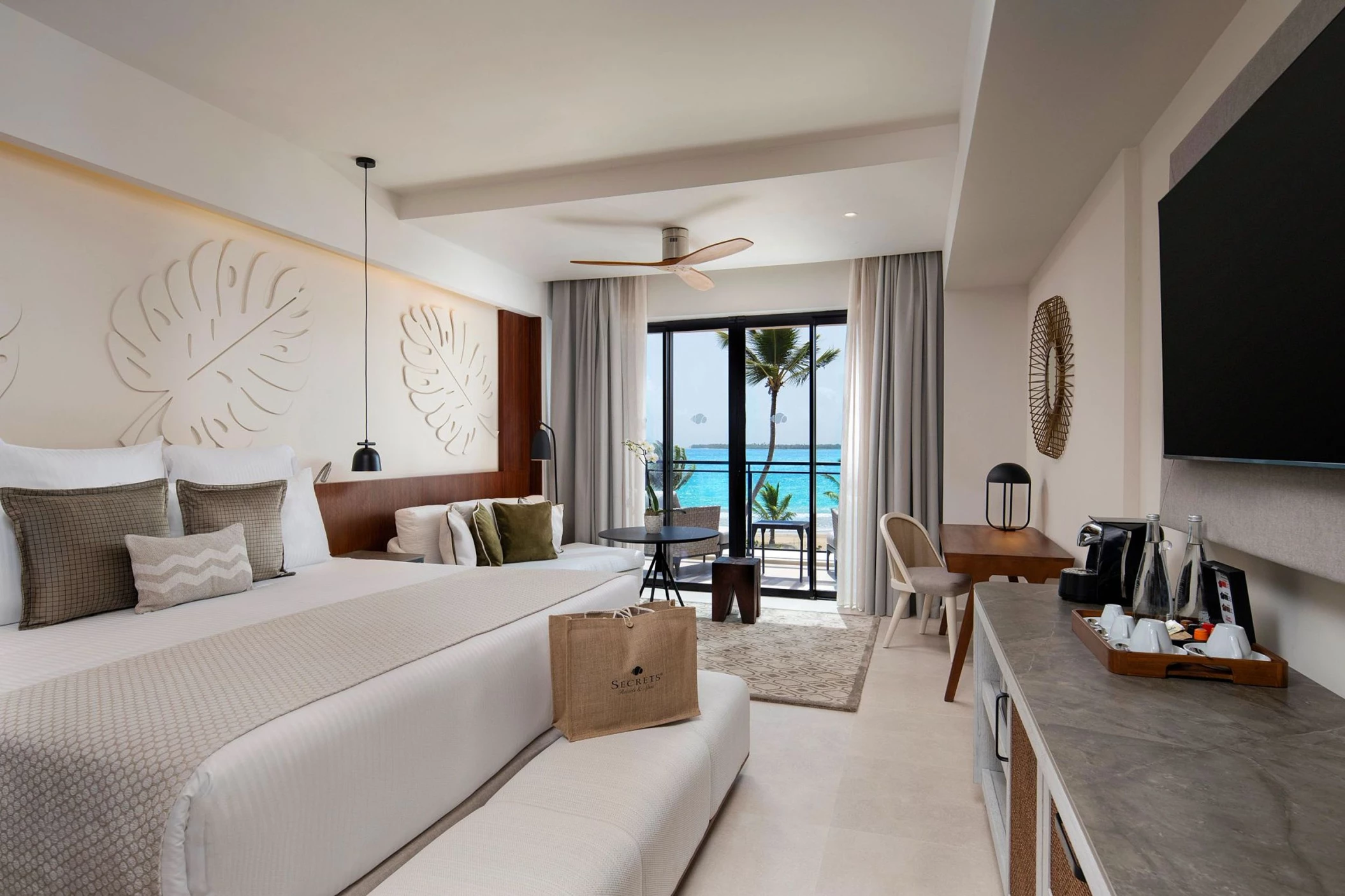 An oceanfront preferred club junior suite with a king-sized bed and balcony with a stunning beach view.