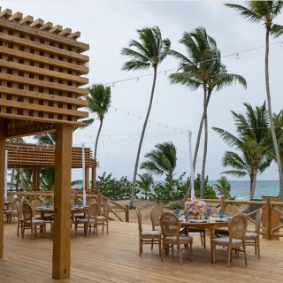 The Secrets Beach Club venue, an outdoor deck with wooden tables, string lights, and an ocean view.