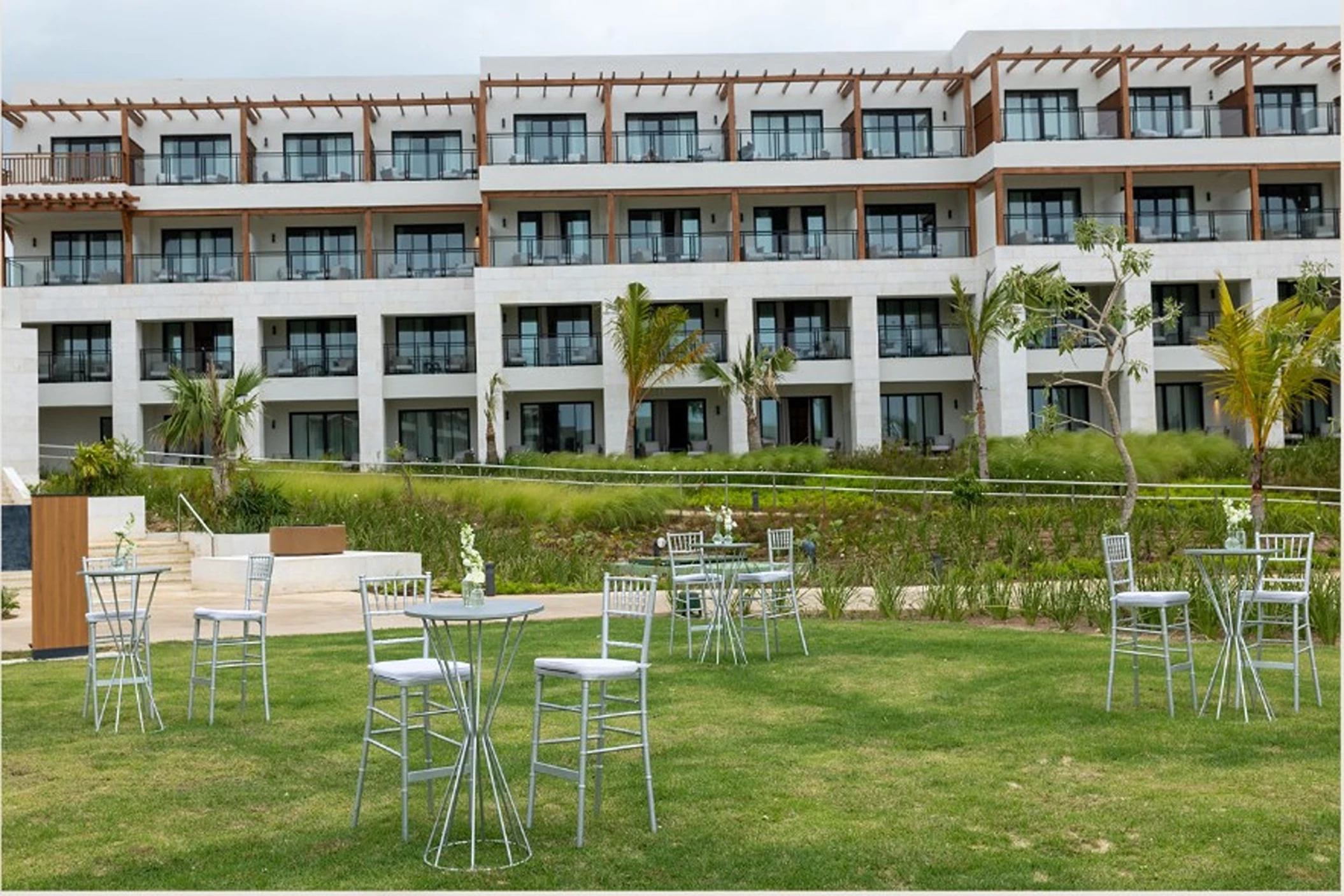 The Secrets Garden Lobby venue, a grassy lawn with cocktail tables in front of a hotel building.