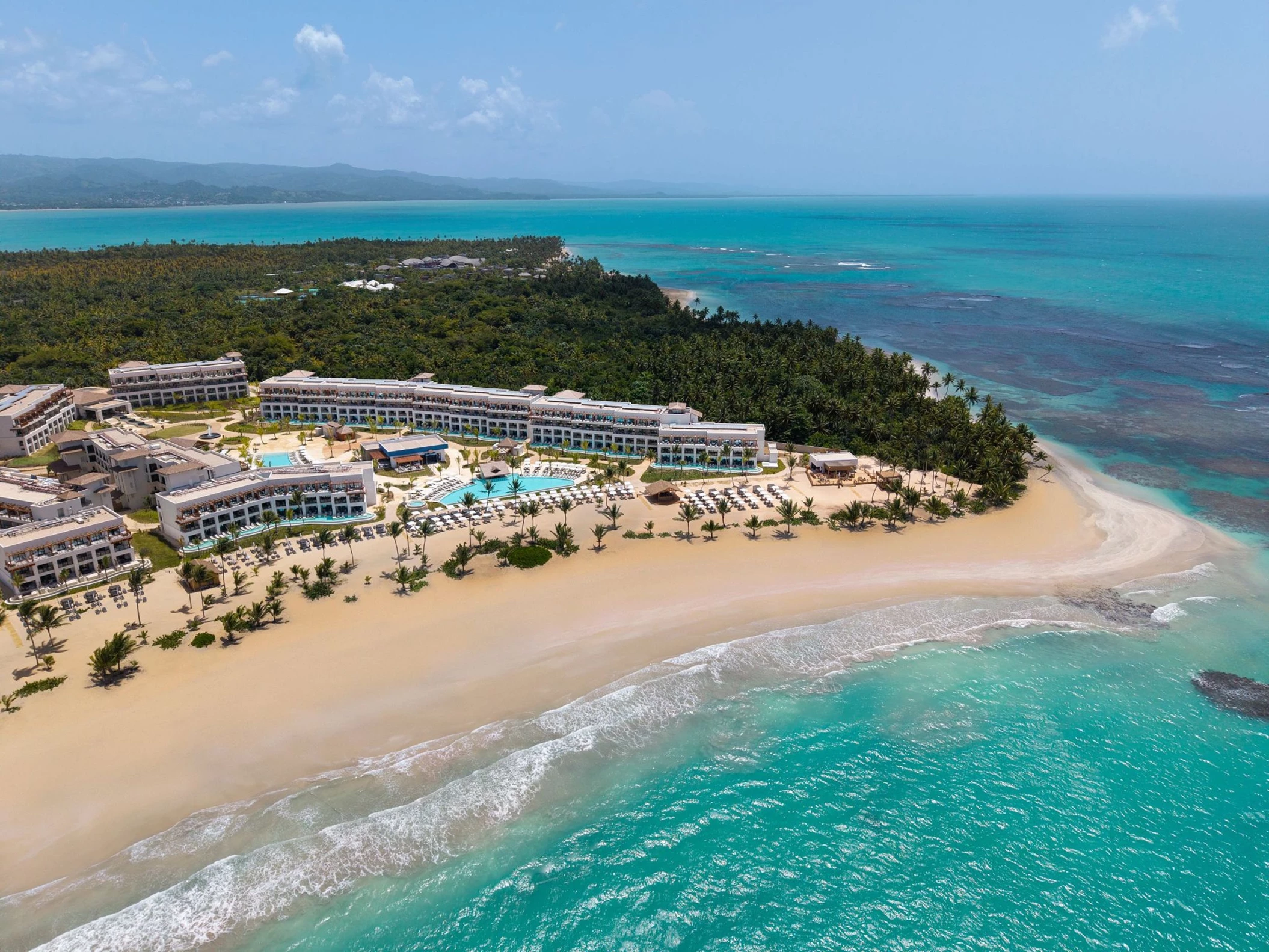 An aerial shot of the entire Secrets Playa Esmeralda resort, showing the long beach and blue water.