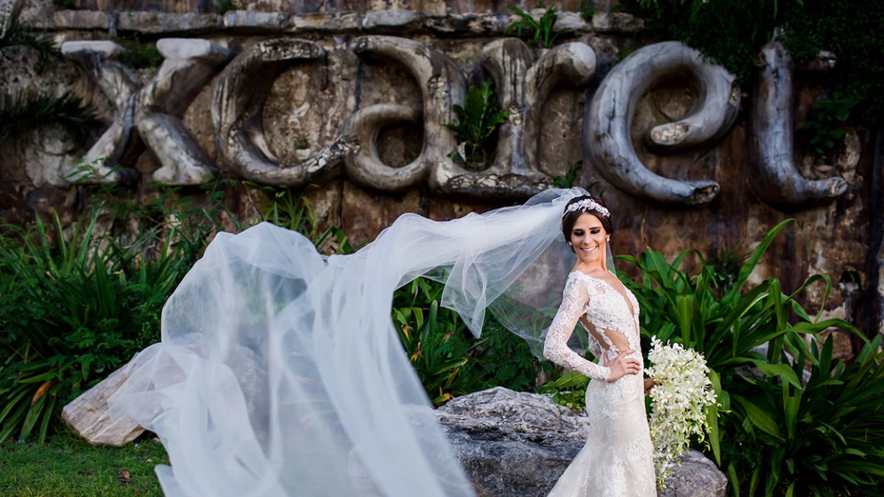 Beautiful bride poses at huge Xcaret sign.