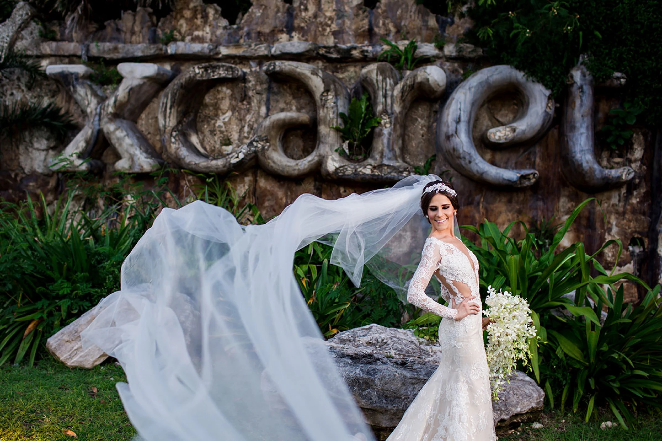 Beautiful bride poses at huge Xcaret sign.