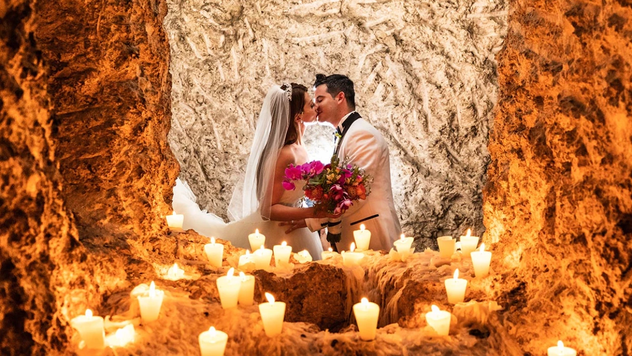 Wedding couple kissing at the light of multiple candles.