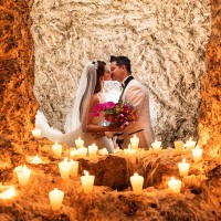 Wedding couple kissing at the light of multiple candles.