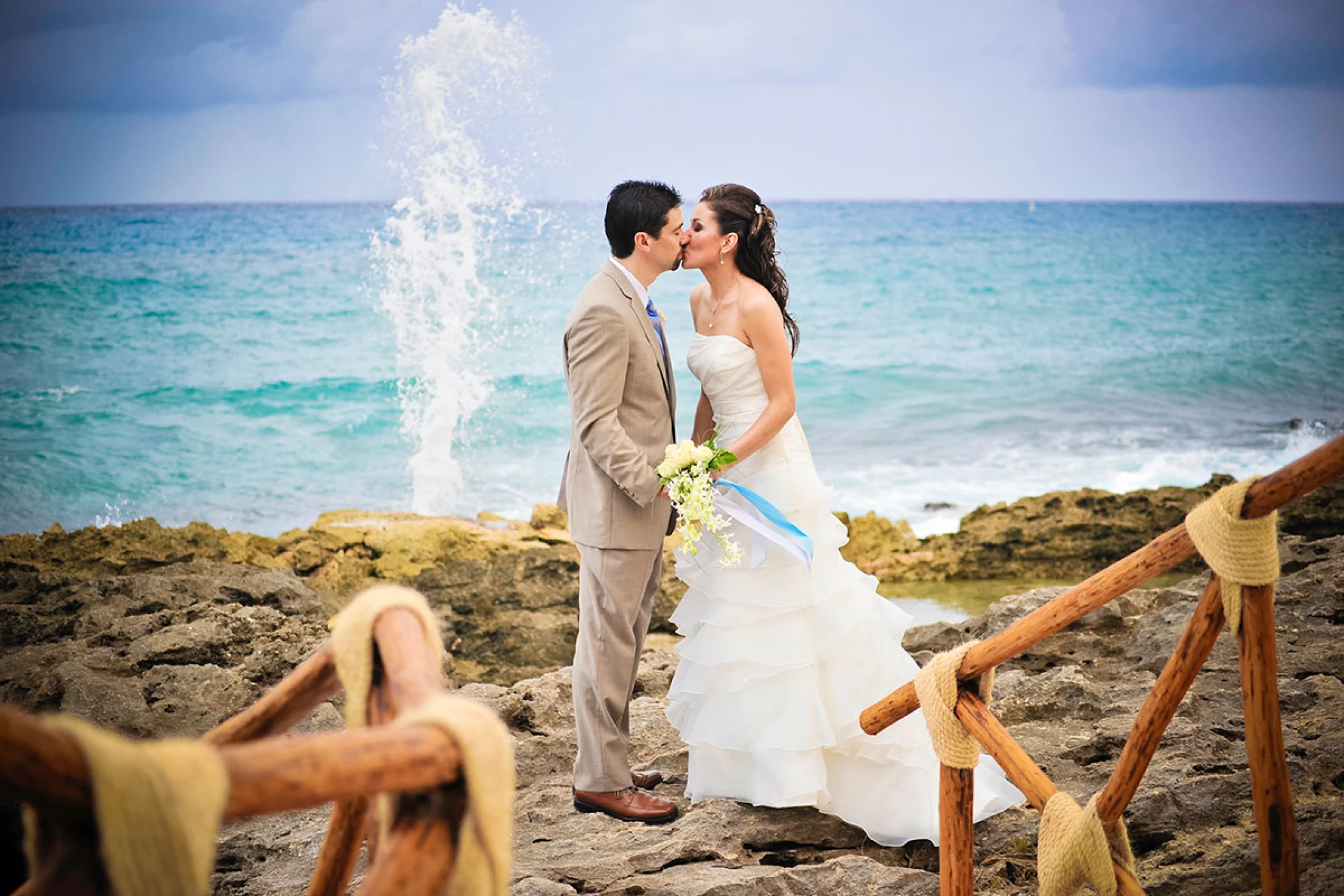 Just Married Couple kisses on a beautiful rocky beach.