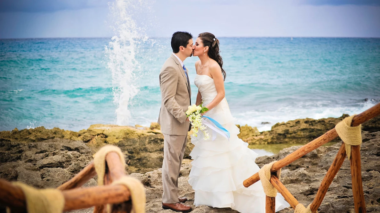 Just Married Couple kisses on a beautiful rocky beach.