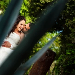 Couple kissing behind an agave plant.