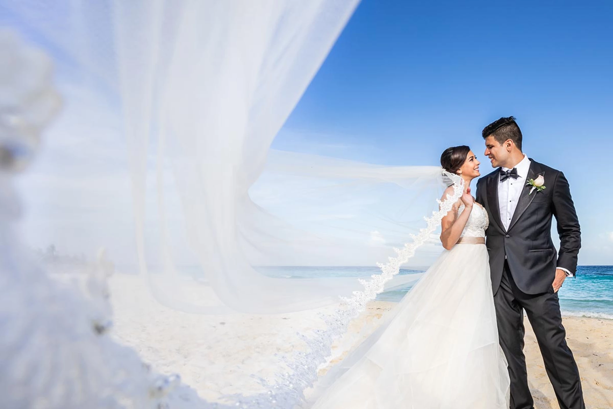 Newly-weds smiling to each other on the beach