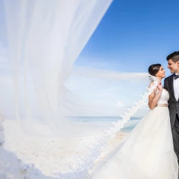 Newly-weds smiling to each other on the beach