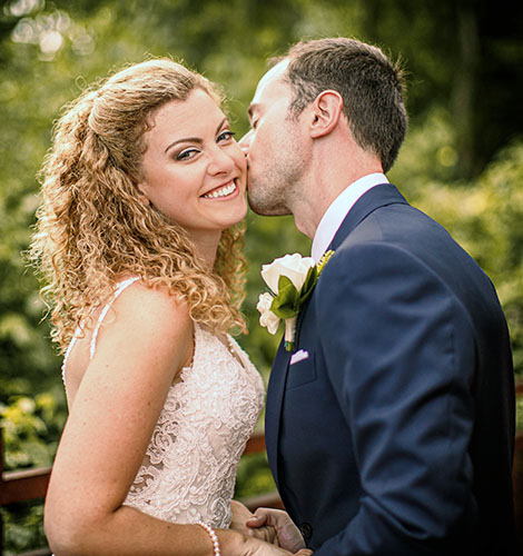 Bride smiles when groom kisses her chick