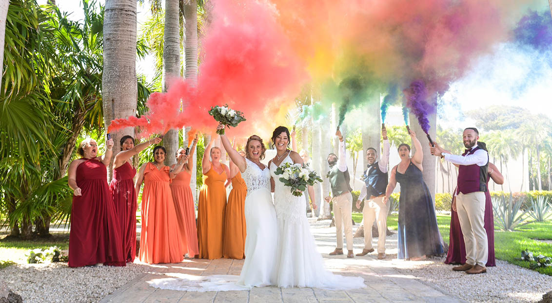 tw brides celebrate their wedding with their wedding party and rainbow color smoke